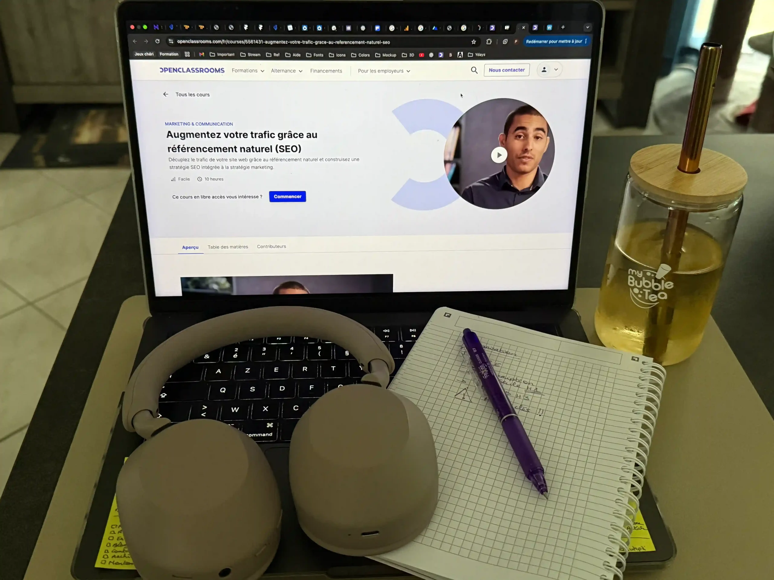 Ordinateur affichant la formation SEO gratuite d’OpenClassrooms « Augmentez votre trafic grâce au référencement naturel », accompagné d’un carnet de notes, d’un stylo et d’un casque audio.