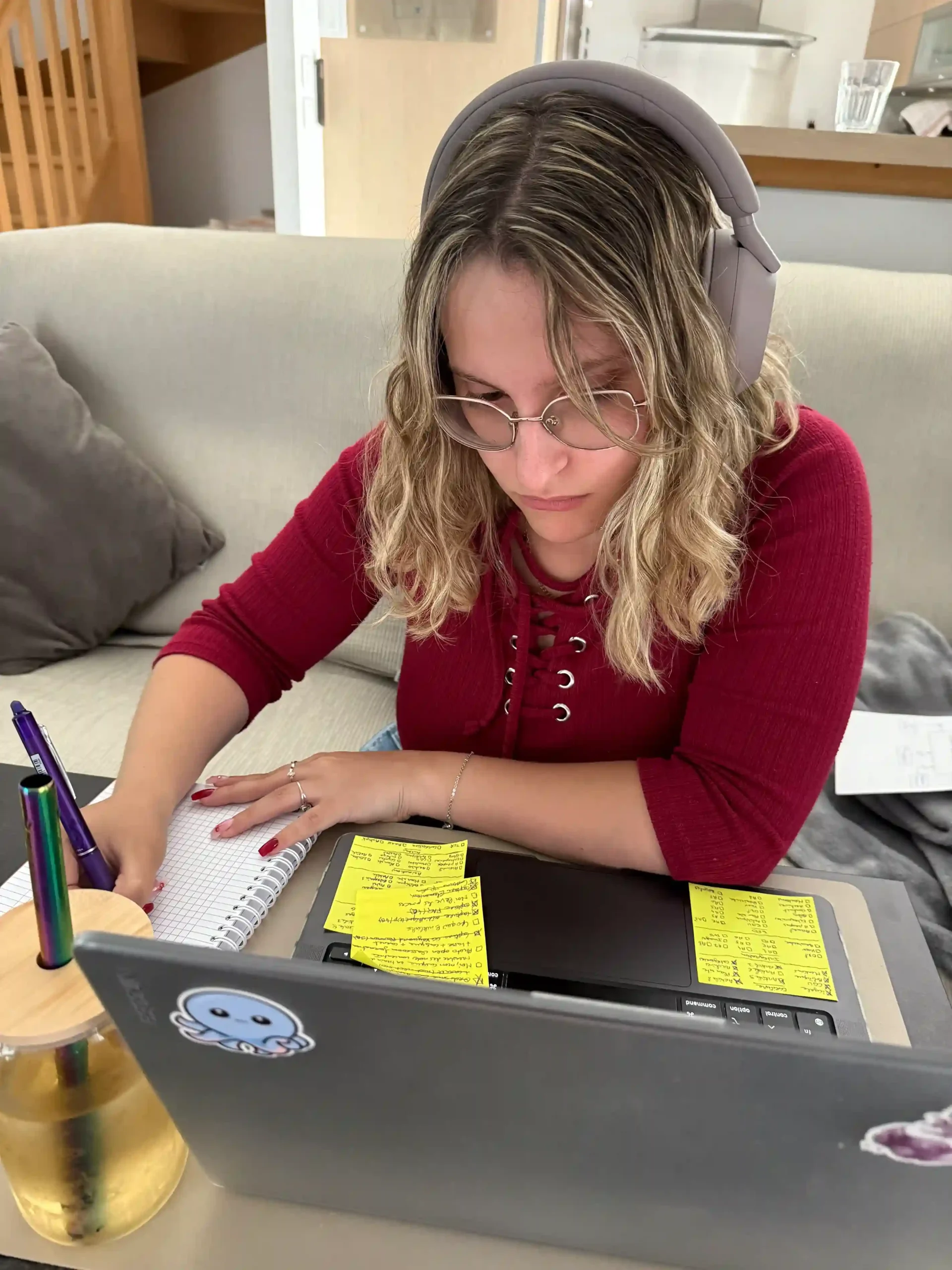 Tiffanie suit une formation SEO gratuite avec casque audio, carnet de notes et ordinateur rempli de post-its pour apprendre à optimiser un site.