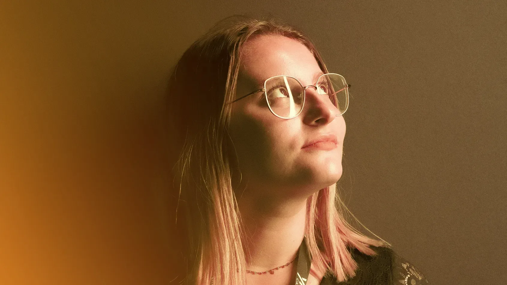 Portrait de Tiffanie avec lunettes, éclairée par une lumière dorée et le regard tourné vers le haut