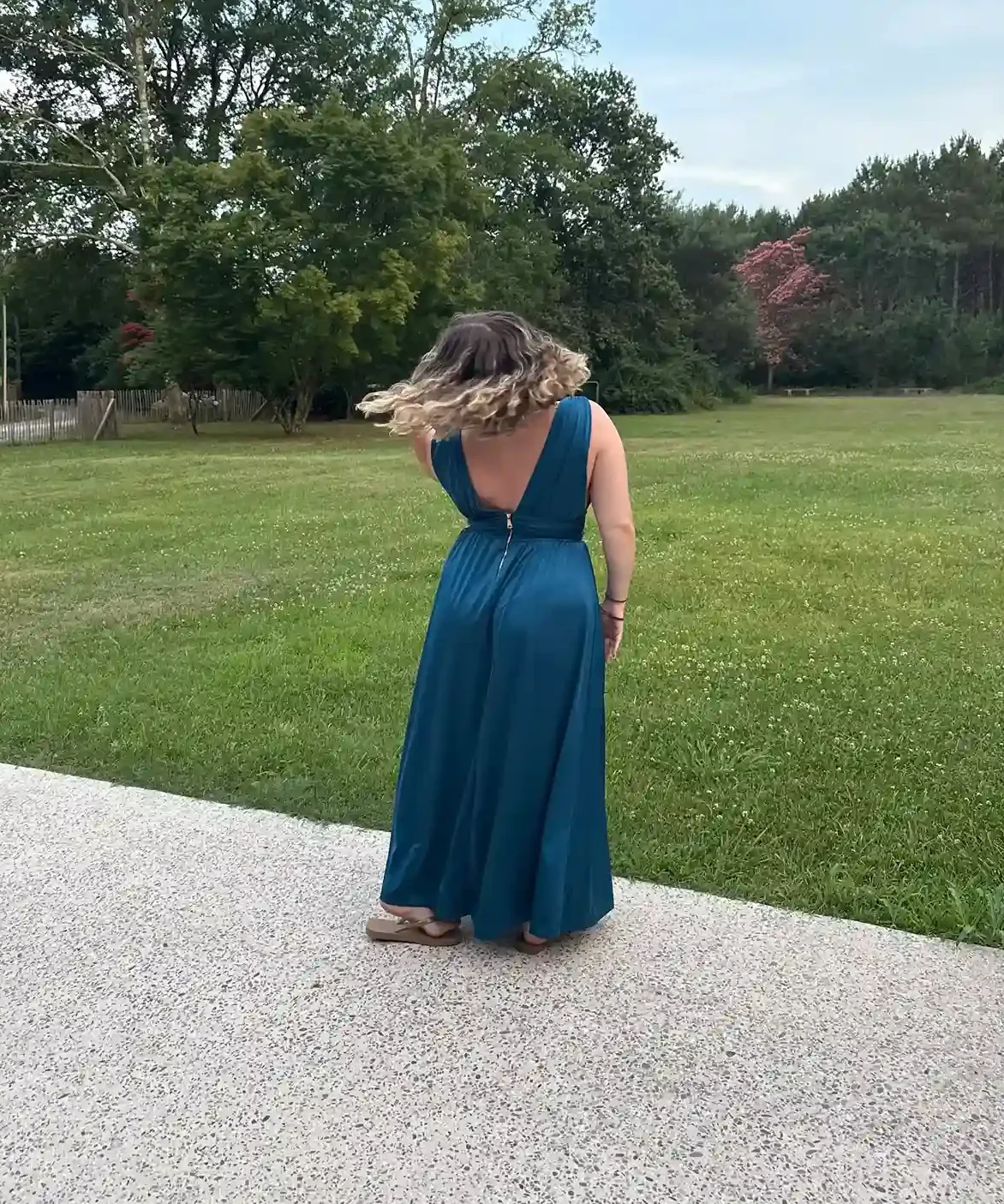 Photo de Tiffanie en robe bleue, de dos, dans un grand jardin verdoyant